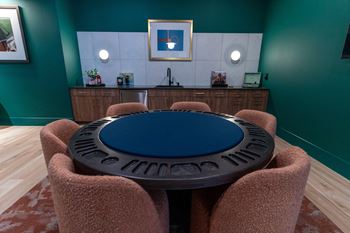 A round table with a blue top is surrounded by brown chairs in a room with green walls.